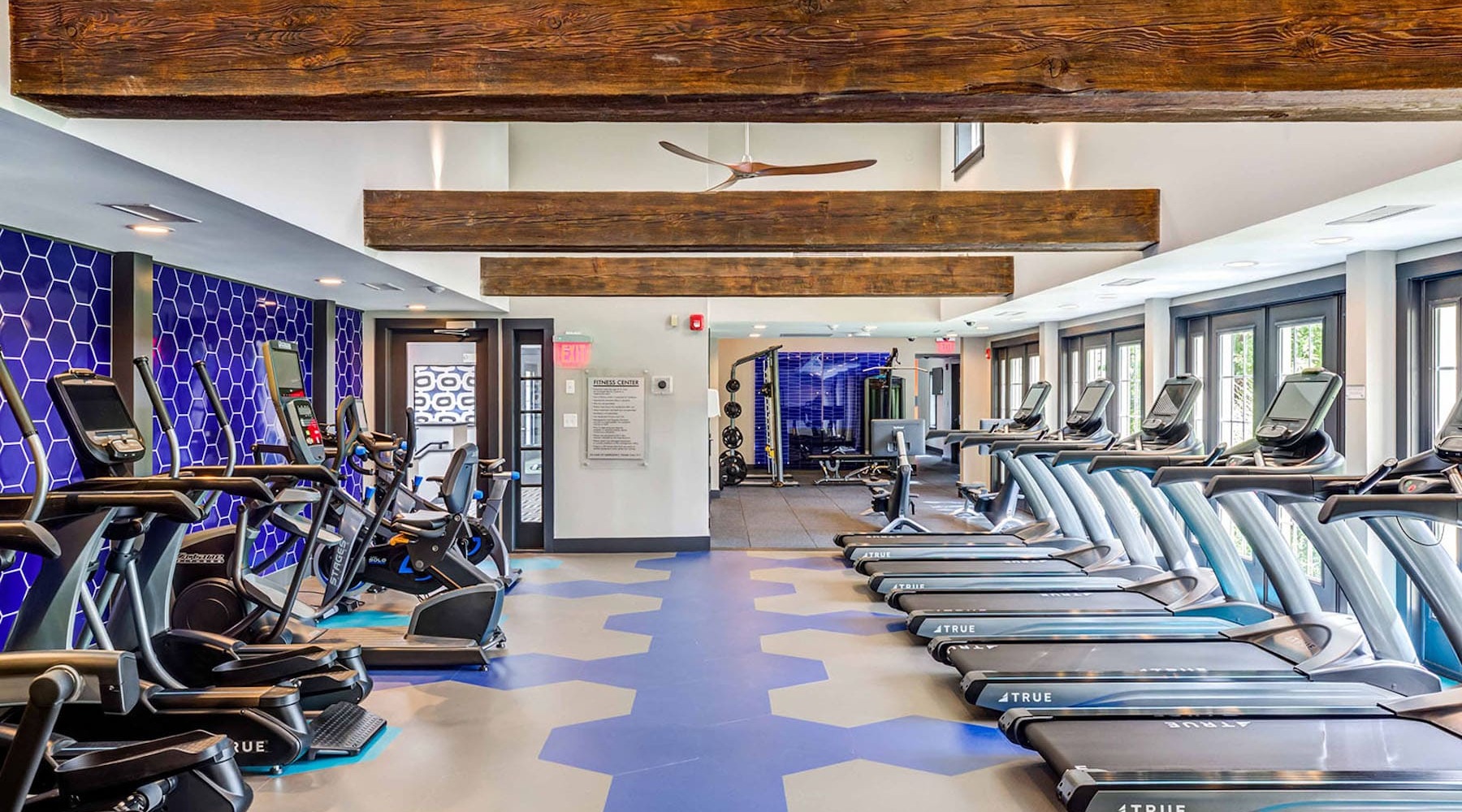 fitness center with rows of treadmills and modern style flooring