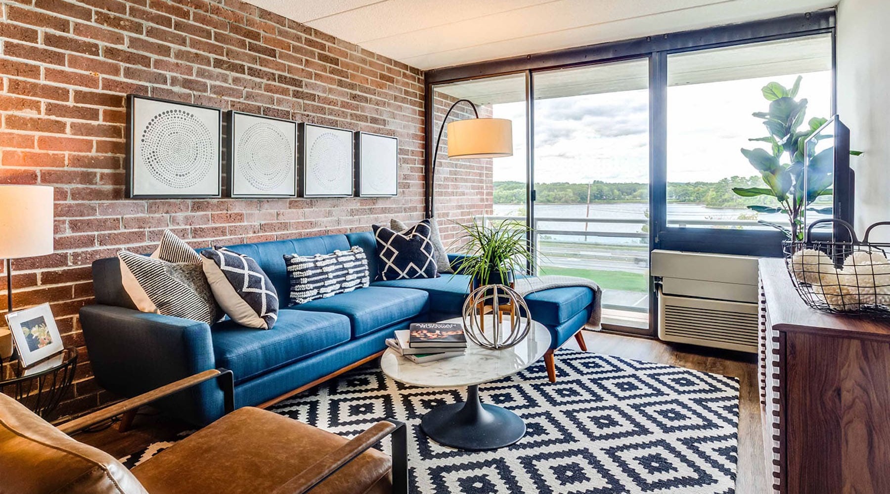 spacious living room area with modern decor and a brick wall