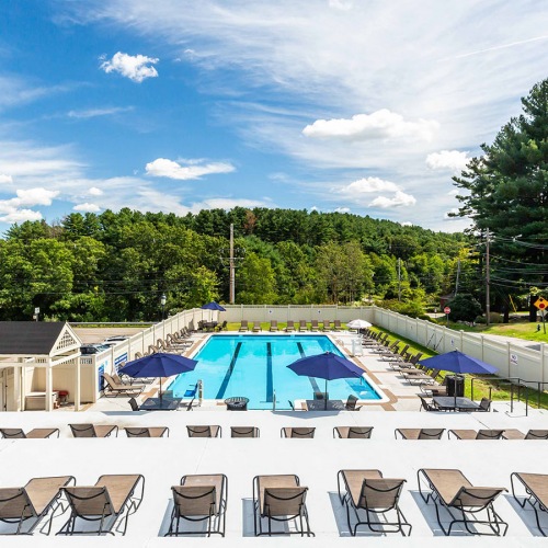 Wide View of our Sun-Soaked Pool and Sundeck the green at 9&90 apartments in framingham pool with reclining seats and lush landscaping